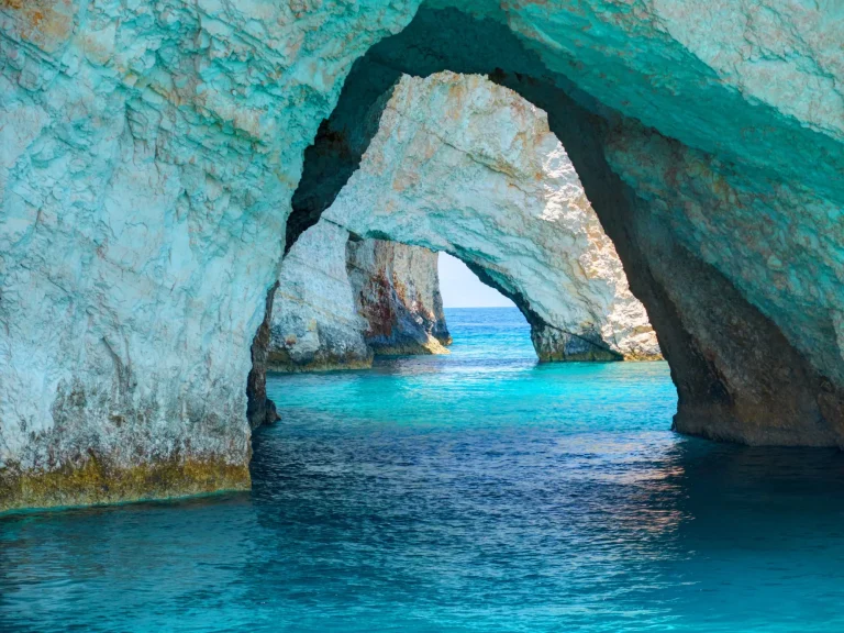 Schöner Blick auf Blue Caves Felsbögen von Sightseeing-Boot mit Touristen im blauen Wasser des Ionischen Meeres in Blue Cave. Insel Zakynthos Griechenland Urlaub Urlaub Ausflüge Touren.