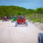 group of buggy vehicles riding on dusty countryside road during extrim tourist trip