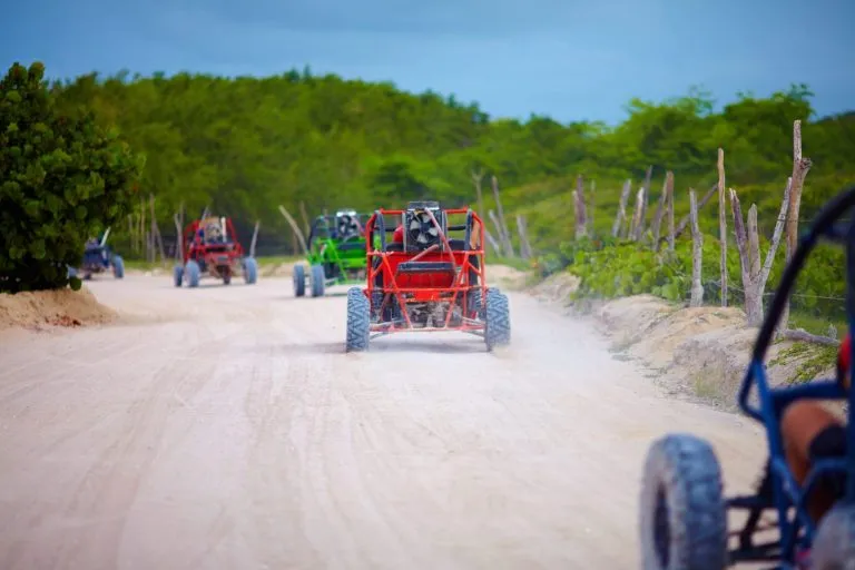groupe de véhicules buggy roulant sur une route de campagne poussiéreuse lors d'un voyage touristique à l'étranger