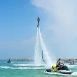 Man posing at new flyboard at Caribbean tropical beach. Positive human emotions, feelings, joy. Funny cute men making vacations and enjoying summer.