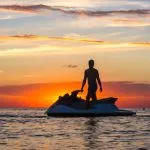 silhouette di un uomo su una moto d'acqua al sole