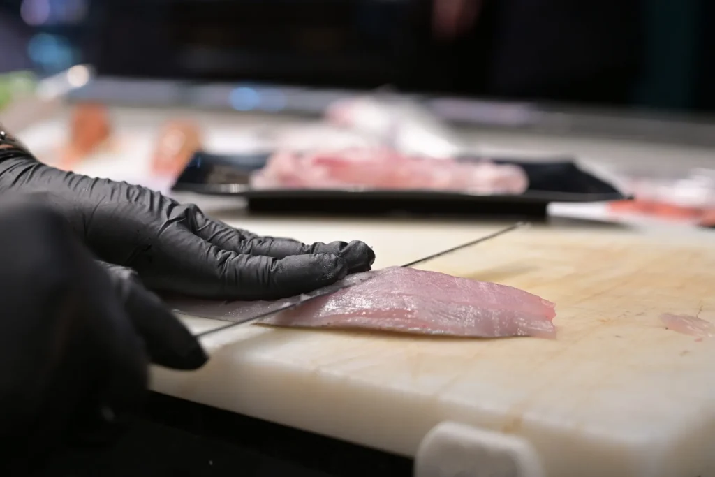 mano con coltello sfiletta un pesce in pescheria
