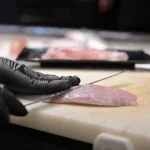 mano con coltello sfiletta un pesce in pescheria