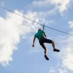 a man descends on a rope, a sport in an extreme park, A man walking along a zip line